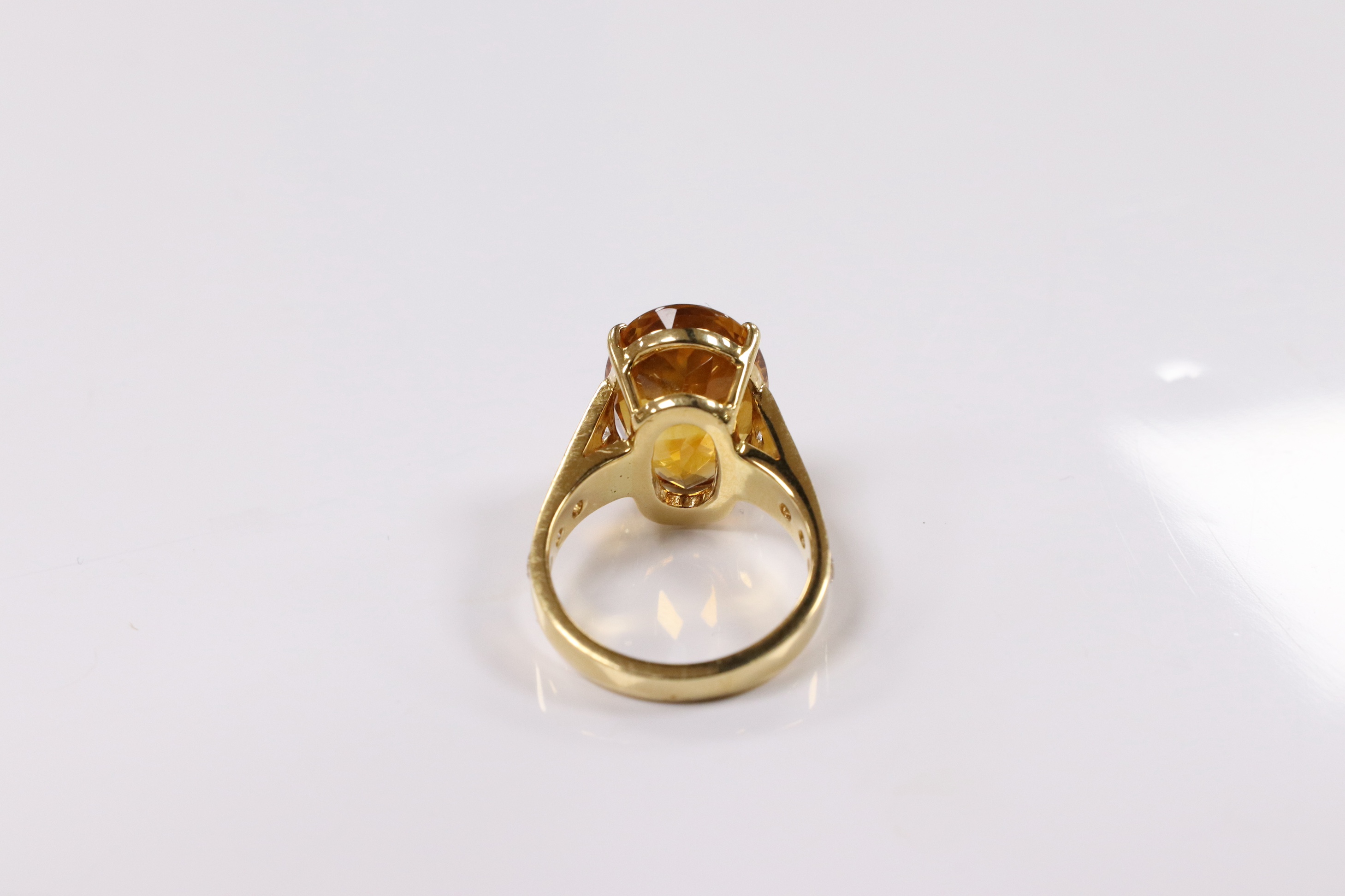 A modern 18k and single stone oval cut citrine set dress ring, with ten stone graduated diamond set shoulders, size K, gross weight 7,7 grams. Condition - good